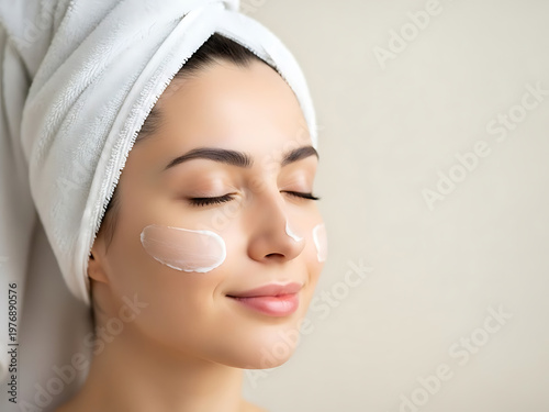 Woman with face cream and towel skincare beauty routine eyes closed spa