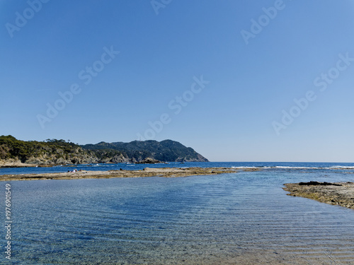 View of rocky southern shore of Gaou island in Le Brusc (Six-Four-les-Plages, Var, France) on clear blue sky day of spring