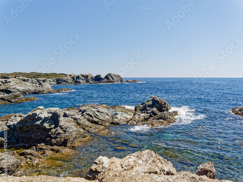 View of rocky southern shore of Gaou island in Le Brusc (Six-Four-les-Plages, Var, France) on clear blue sky day of spring