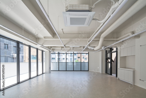 Open white room with windows and exposed services in shell interior