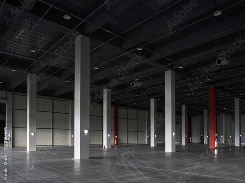 Vast dim warehouse hall with black ceiling and tall columns