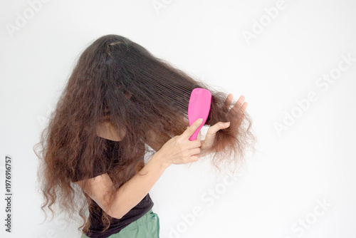 woman with curly hair is combing her hair.