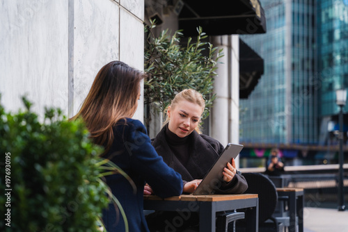 Colleagues discussing business using a tablet outdoors in urban setting