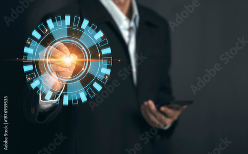 Businessman holding smartphone and touching futuristic digital interface with glowing circle, technology concept, data analysis, innovation, and digital transformation
