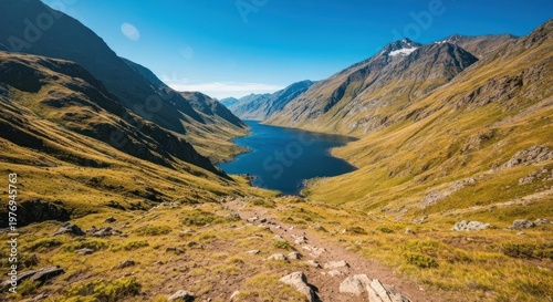 Scenic mountain valley with lake, trail, and sunny blue sky