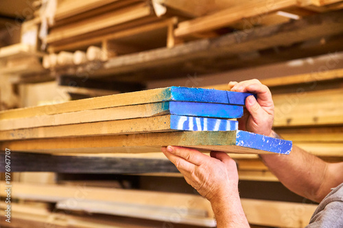 Foto Carpenter's hands picking up boards stacked high up