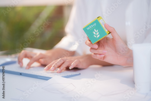 Hand holding cosmetic packaging mockup box, graphic designer and development branding project, sketch and layout artwork, business startup planning creative for skincare product label advertising.