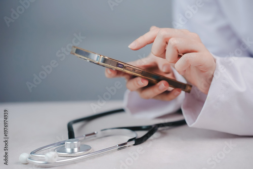 Hands of a healthcare provider using a mobile phone for virtual consultation. Telehealth services, digital medicine, and remote patient monitoring concept in a modern clinic office setting.