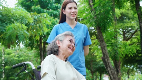 Caucasian female caregiver encouraging senior patient on wheelchair in garden, professional nurse support elderly woman for rehabilitation and mental health therapy outdoors, medical and assistance.