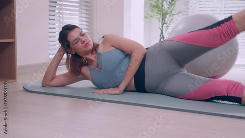 Young caucasian woman doing fitness workout on mat at home, side leg raise exercise for strength and flexibility, healthy lifestyle and bodyweight training, practicing yoga exercise and motivation.