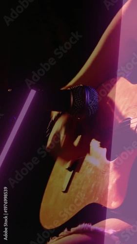 Vertical video: Player bringing mic to hole, performing, causing zoom, strumming, neon-lit guitar