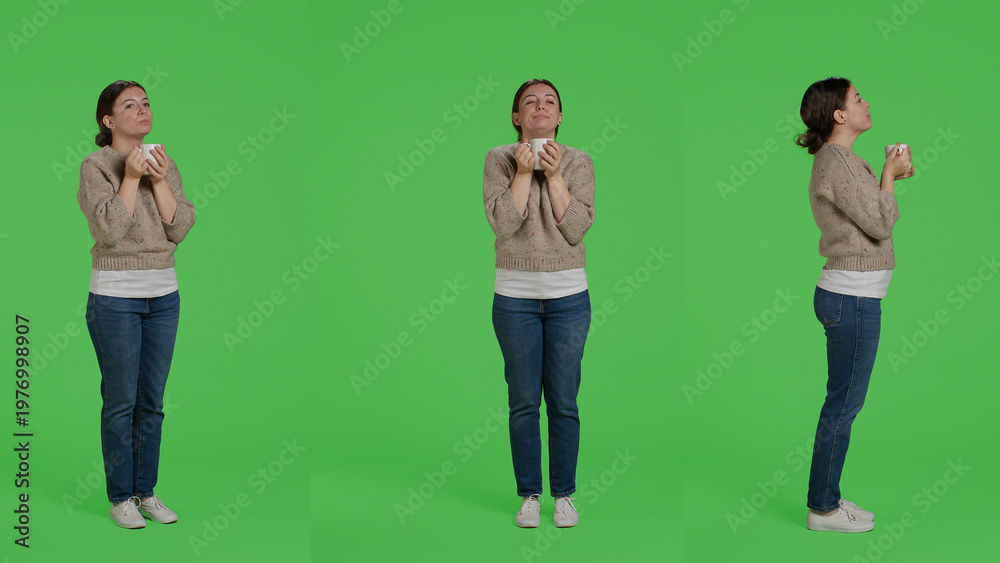 Obraz premium Caucasian girl drinking cup of coffee over full body greenscreen background, holding caffeine drink in studio. Young woman enjoying caffeine beverage on isolated greenscreen, portrait.