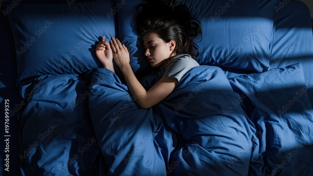 Fototapeta premium Peaceful young woman sleeping in blue bedding, deep REM sleep for circadian rhythm health