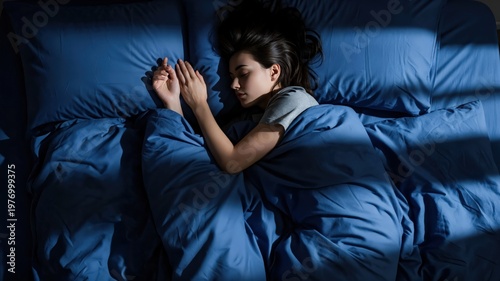 Peaceful young woman sleeping in blue bedding, deep REM sleep for circadian rhythm health