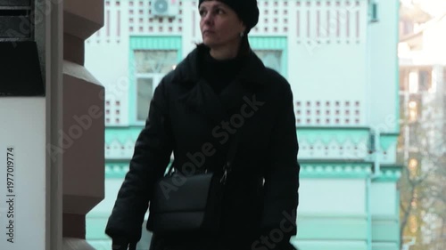 Elegant Mature Woman in Black Coat and Beret Walking in European City Street