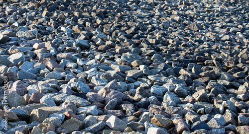Background texture of many small grey and brown granite rocks on the ground for construction site or garden landscape design concept