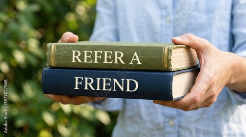 Person holding two books with Refer a Friend text on covers.