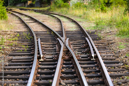 Railroad turnout switch with converging and diverging rails on weathered ties and gravel, evoking choices, crossroads, change and a journey toward different futures