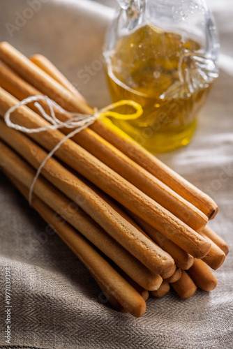 Foto Rustic Grissini Breadsticks Bundle Tied With String on Linen Cloth, Closeup Food