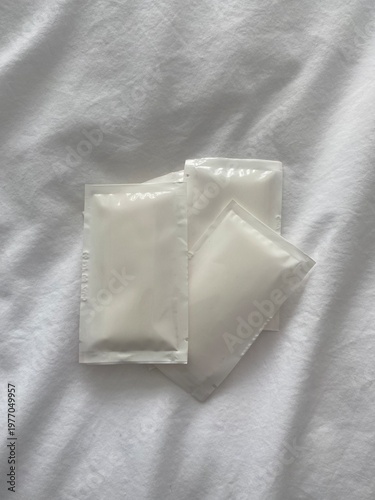 Minimal wet wipe sachets on soft fabric background, hygiene and personal care concept