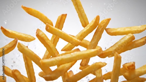 Delicious golden french fries scattered in mid-air with water droplets against a white background