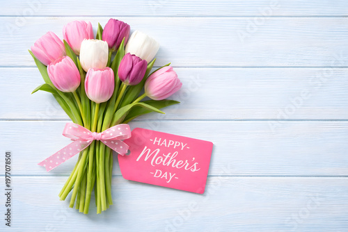 Bouquet of colorful tulips with a mothers day gift tag on a wooden background