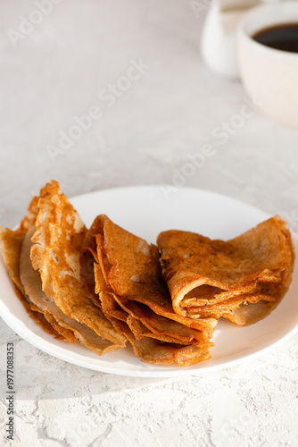 Gluten free crepes, sugar and dairy free with cup of coffee. Healthy thin pancakes on white plate. Vertical orientation.