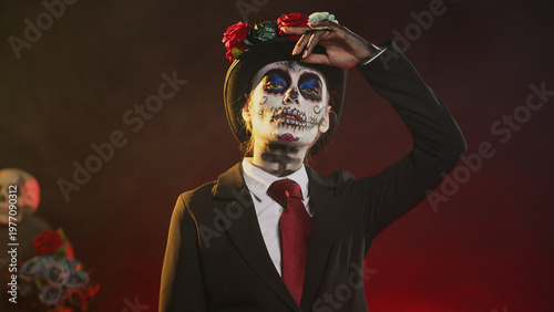 Spooky goddess in halloween costume with skull make up celebrating holy mexican tradition, posing in studio. Looking like lady of death at santa muerte ritual celebration. Handheld shot.