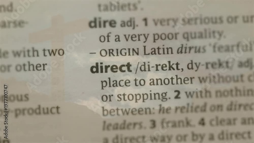 Lens tightening focus on dict column, revealing direct term with faint sky reflection for education