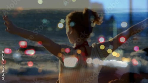 Woman raising arms and opening outward, starting bokeh overlay, embracing sea breeze for health