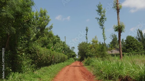 Driving pov on a rural red dirt road in a developing country during a sunny day