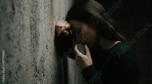 Distressed Woman Leaning Against Concrete Wall Holding Worry Stone Finding Grounding Relief During A Panic Attack
