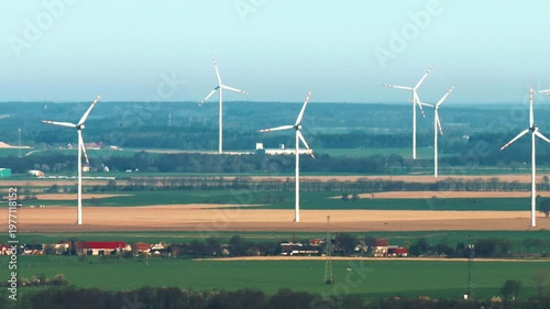 Zoom view of spinning wind turbines in Lower Silesia from distance, sunny and windy weather
