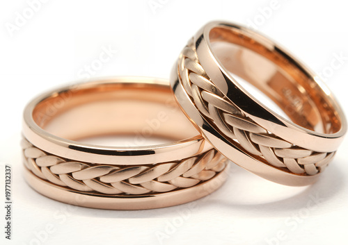 Two rose gold wedding rings featuring a detailed woven braided on a white background