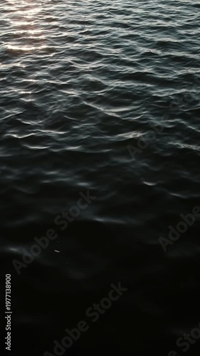 Dark mysterious video of slow breeze on water. Still lake water and small waves.
