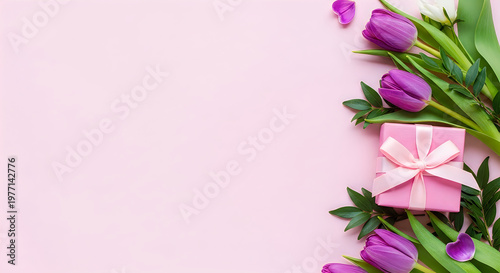 A pink gift box with a ribbon surrounded by purple tulips on a light pink background.