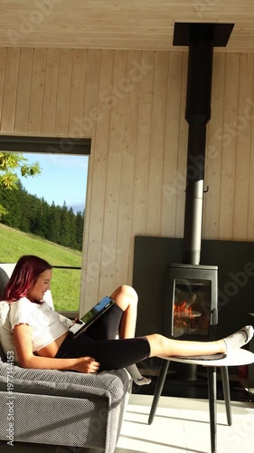 Girl sitting on couch looking at tablet while resting leg on table in modern living room