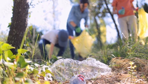 Принти на полотні Volunteers picking up plastic waste and trash from a forest floor, focusing on e