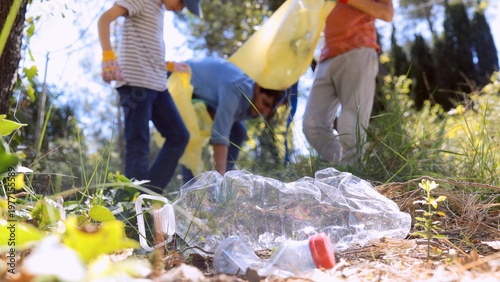 Tableau sur toile Group of adults and children volunteering outdoors, collecting plastic bottles a