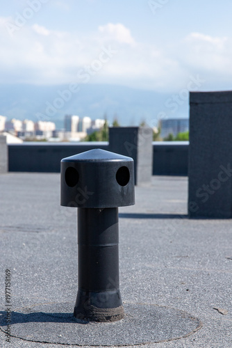 Vertical shot of a plastic roof aerator for moisture removal on a flat roofing system with bitumen waterproofing.