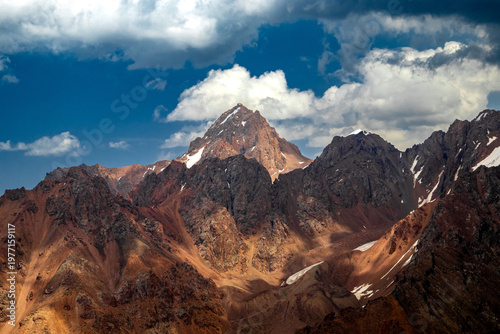 Wide mountain range panorama featuring Maloalmatinsky Peak. Dramatic lighting on rocky ridges and alpine terrain in Trans-Ili Alatau near Almaty.