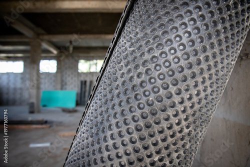 Close-up of black dimpled waterproof membrane roll at an indoor construction area for foundation and wall protection.