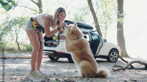 Happy young woman giving treats to dog outdoors while training