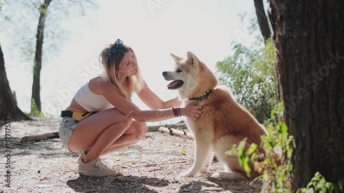 Happy young woman petting her dog on a walk