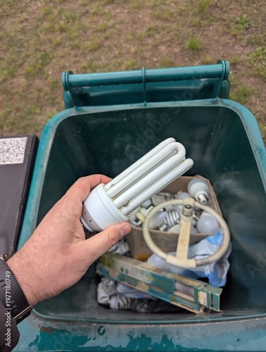 Hand throwing used fluorescent lamps for recycling into the container bin. Circular economy concept.