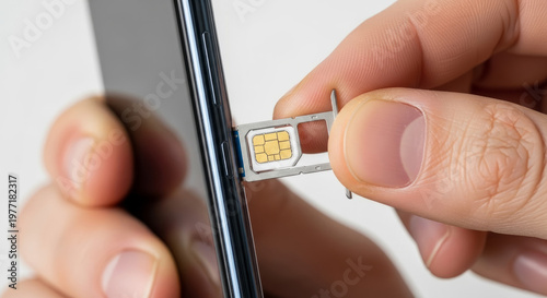 Hand inserting SIM card into smartphone in a modern technology setup with focus on connectivity and communication