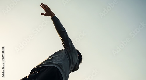 Silhouette of a person reaching up towards the sky.