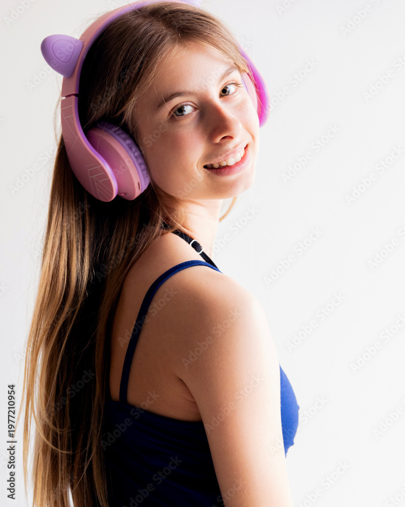 Naklejka premium Studio Portrait of a Blonde Pre-teen Girl in Blue Clothing Wearing Pink Headphones