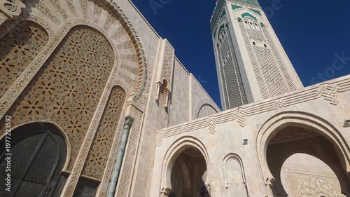 pan view of Hassan II Mosque against sky , Hassan II Mosque minaret looking up through arches - Hassan II Mosque minaret upward view through ornate arches Casablanca, Morocco
