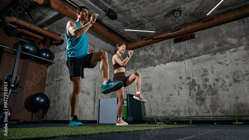 Tableau sur toile Man and woman performing high knee exercise during functional training in gym